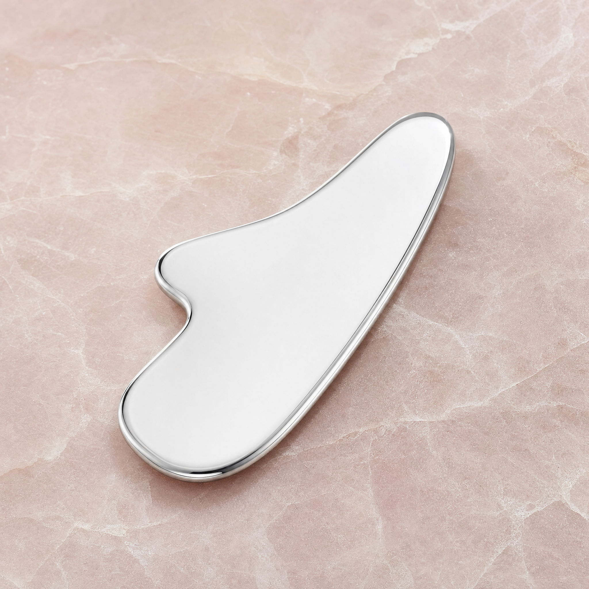 Stainless-steel gua sha on pale rose stone
