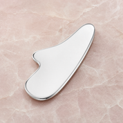 Stainless-steel gua sha on pale rose stone